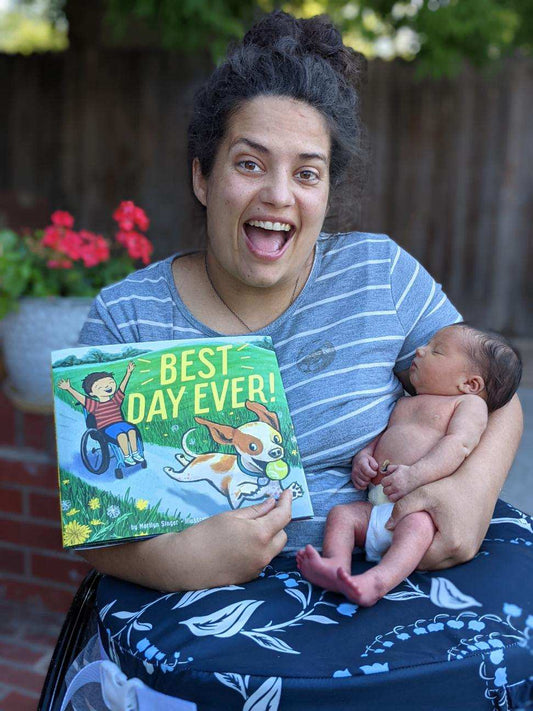 Leah Nixon holds her first illustrated book "Best Day Ever!" and her four day old daughter. Leah has a huge smile on her face. 