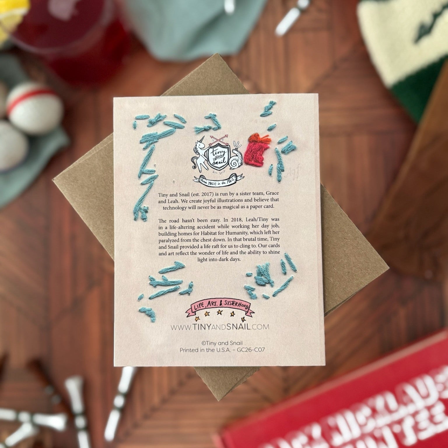 Greeting card back with embroidery detail with decorative elements on a wooden surface