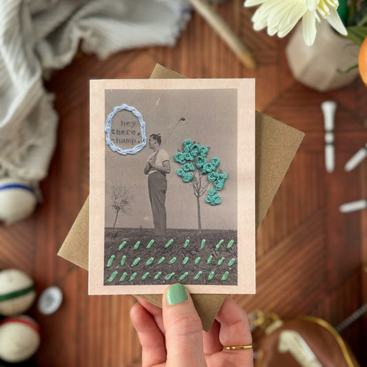 Hand holding a greeting card with decorative elements on a wooden surface.