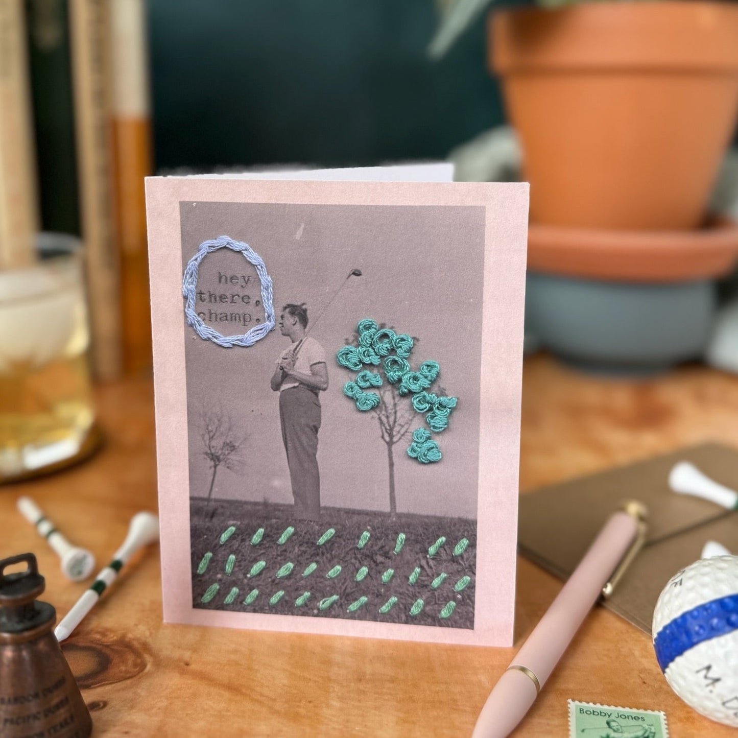 Greeting card with a design of a person golfing near a tree on a wooden surface.