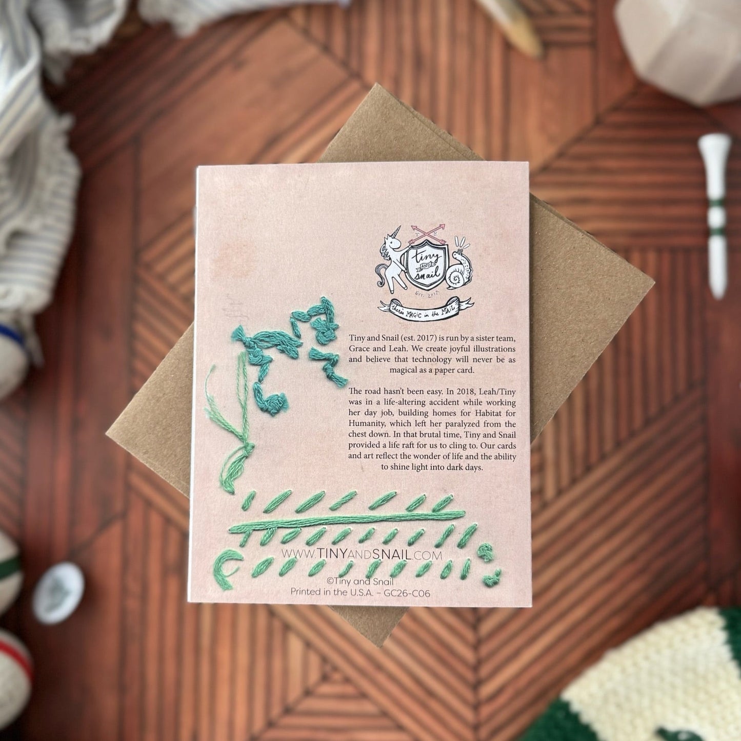 Pink card with green text and graphics on a wooden surface