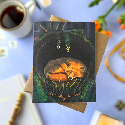 Greeting card with fox illustration on a blue surface with coffee and candles.