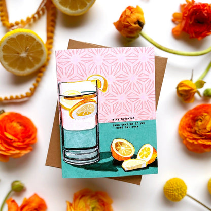 Greeting card with a drink illustration surrounded by lemons and flowers on a white background