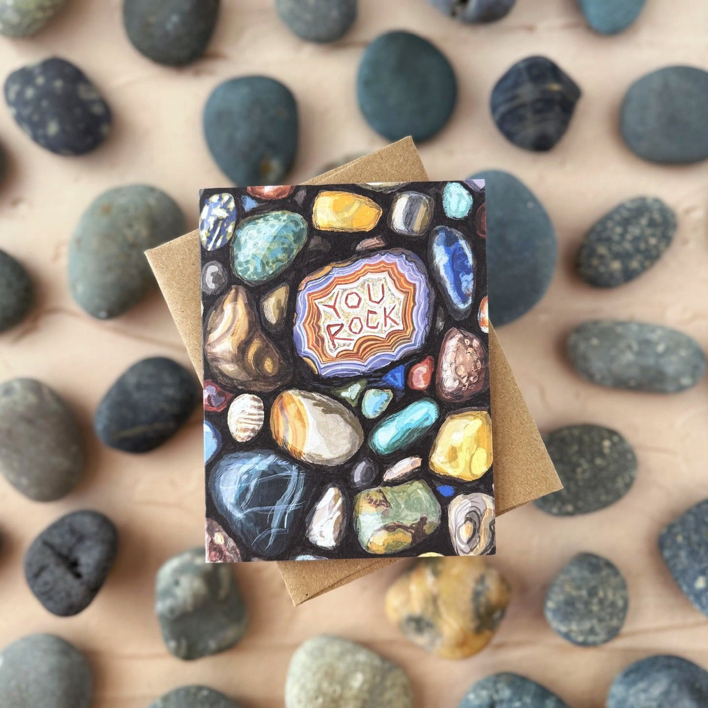 Greeting card with a 'You Rock' design on a bed of small rocks.