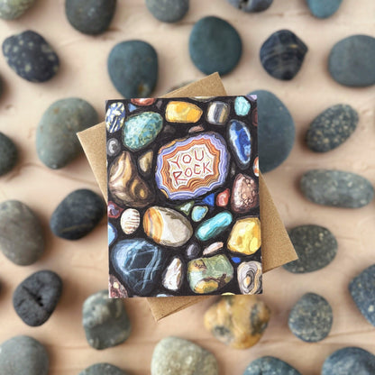 Greeting card with a 'You Rock' design on a bed of small rocks.